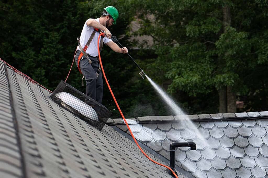 A Roof Maxx dealer carefully sprays the rejuvenation treatment on architectural shingles.