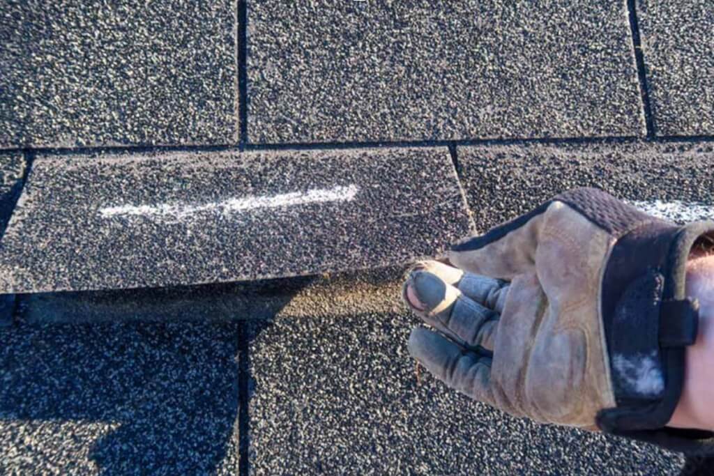 Roofer showing how a shingle lifts away from the roof.