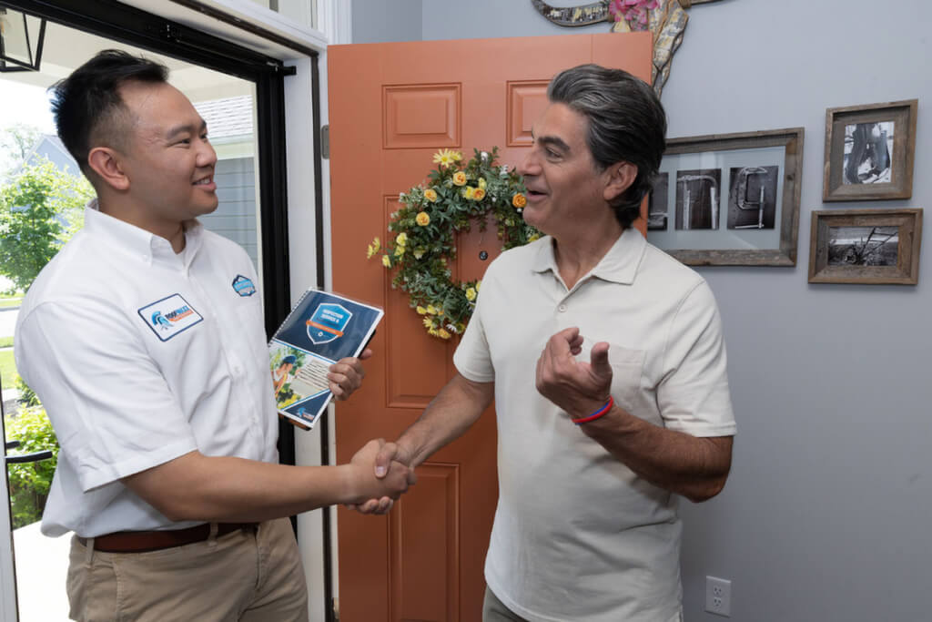 A Roof Maxx dealer introduces himself to a brand-new client in the doorway of his home.