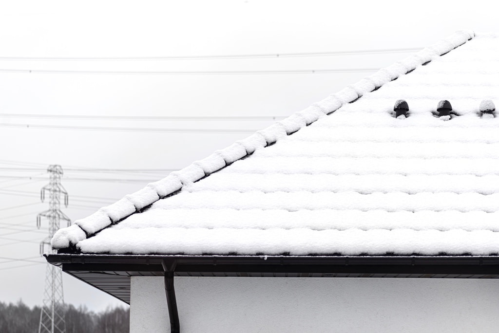 Residential roof with asphalt shingles covered in snow during winter