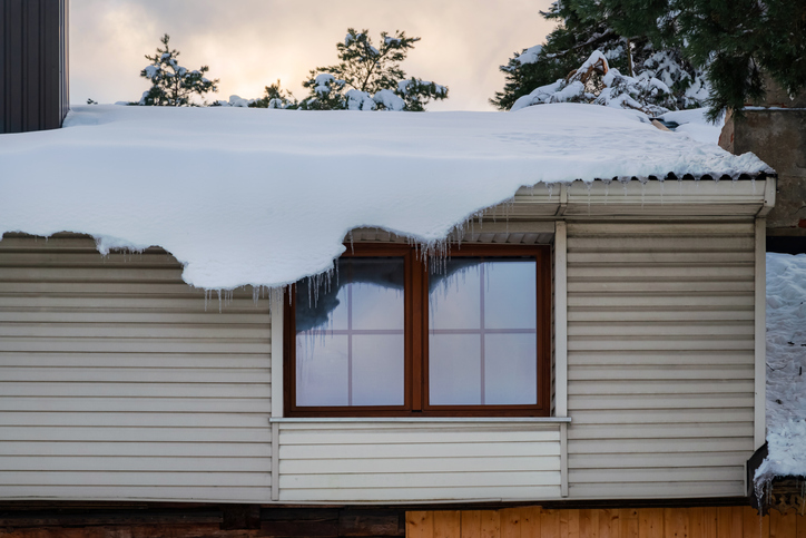 Thick layer of snow hanging off the edge of the roof.