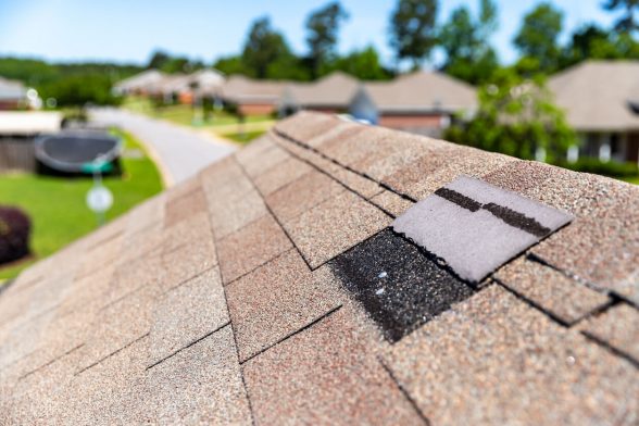 Missing shingle near the ridge of an asphalt roof.