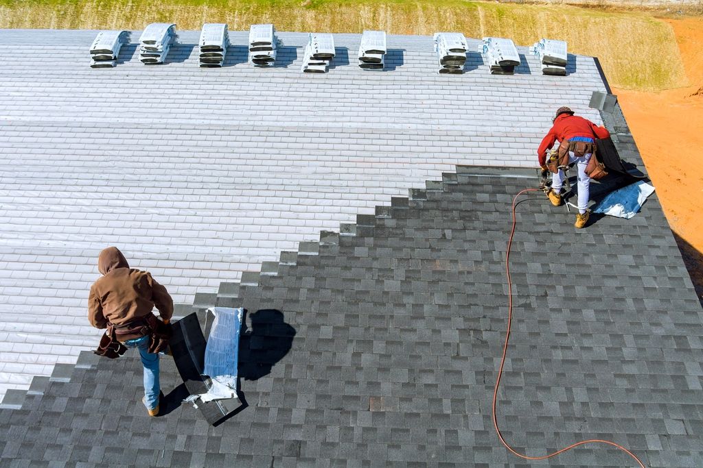 Roofers installing new shingles on residential property