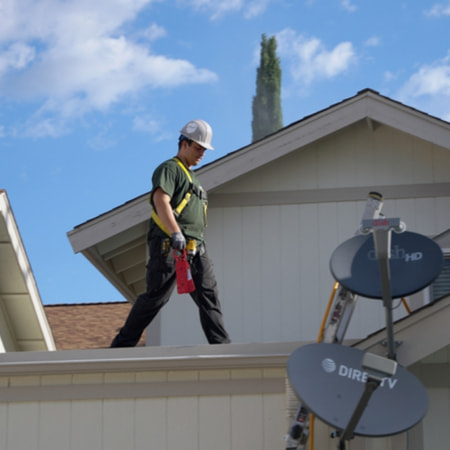 A Roof Maxx dealer walks across a customer's roof during a roof inspection