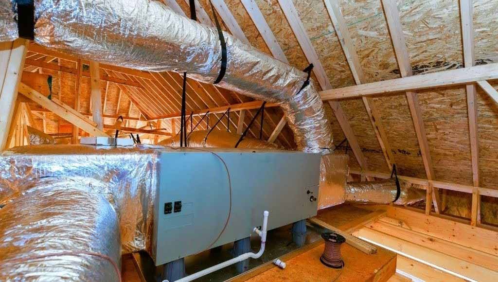 A large HVAC system installed inside an attic, with ductwork visible.